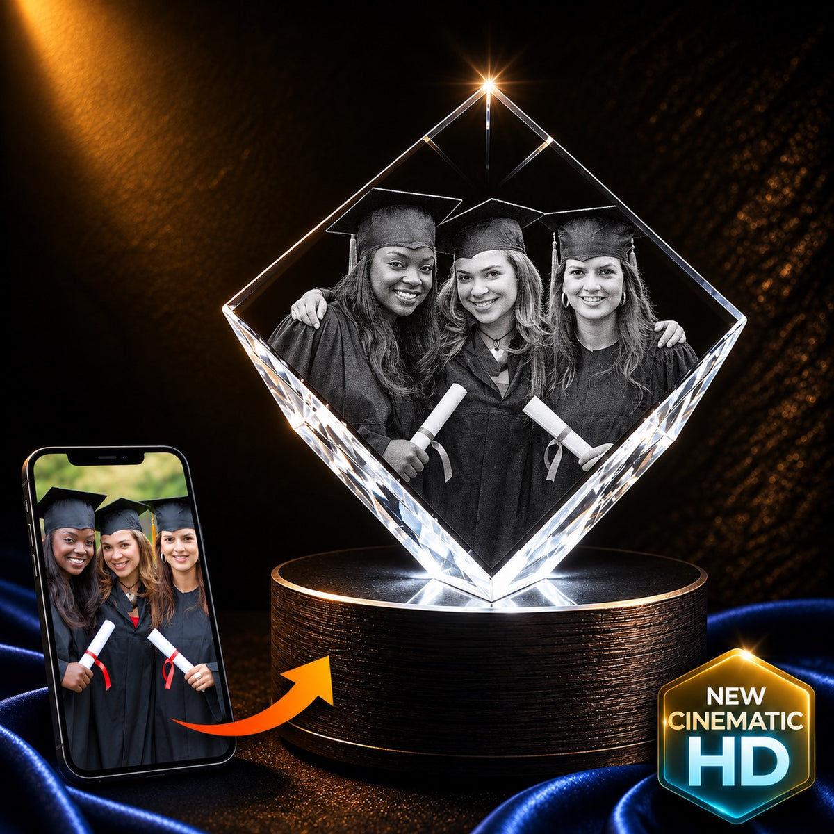 A diamond-shaped acrylic photo lamp on a cylindrical base, displaying a black-and-white graduation photo of three women. A smartphone on the left shows the source photo, with an orange arrow indicating the projected image.